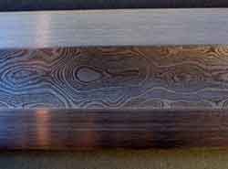 A piece of Damascus steel shows the characteristic wavy 'damask' pattern. 